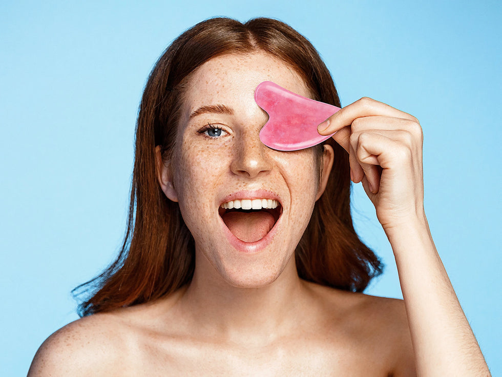 girl smiles and holds a Gua Sha over her eye